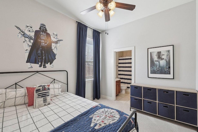 bedroom featuring light colored carpet, ensuite bathroom, baseboards, and ceiling fan