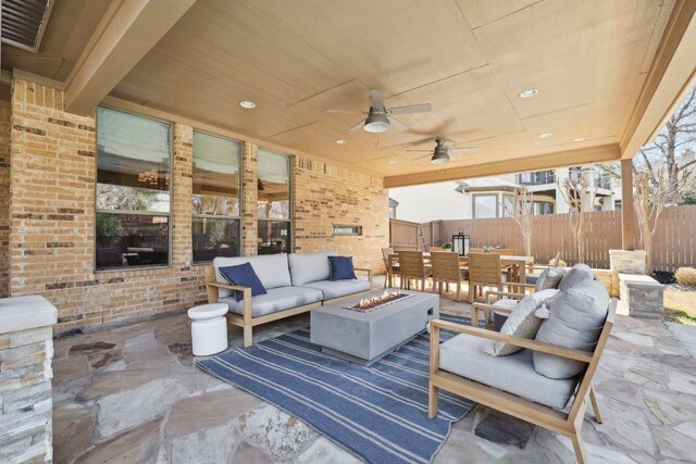 view of patio featuring an outdoor living space with a fire pit, outdoor dining space, a ceiling fan, and fence