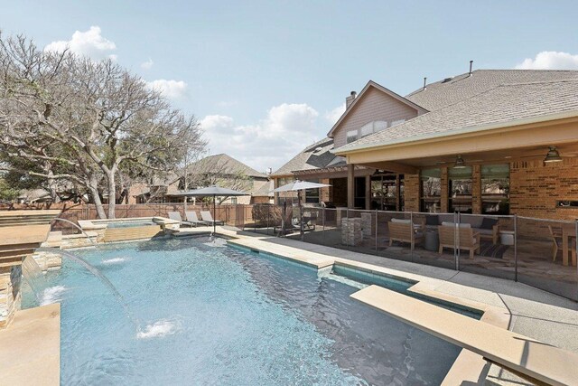 view of pool featuring fence, outdoor lounge area, a jacuzzi, a patio, and a diving board