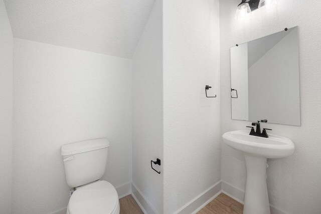 1601 Cardinal Ln, Round Rock, TX 78681 - bathroom with toilet, wood finished floors, a sink, vaulted ceiling, and baseboards