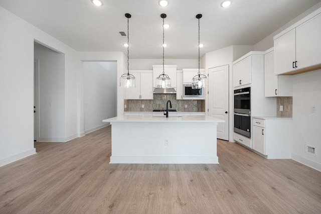 1601 Cardinal Ln, Round Rock, TX 78681 - kitchen featuring built in microwave, double wall oven, backsplash, a sink, and light countertops