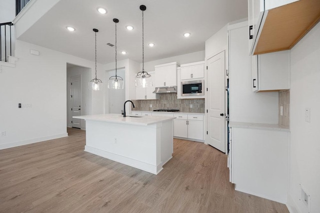1601 Cardinal Ln, Round Rock, TX 78681 - kitchen with stainless steel microwave, a sink, decorative backsplash, light wood-type flooring, and recessed lighting