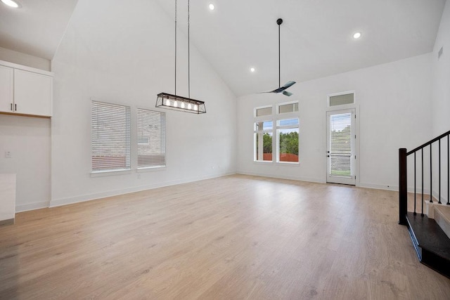 1601 Cardinal Ln, Round Rock, TX 78681 - unfurnished living room featuring high vaulted ceiling, stairs, ceiling fan, light wood finished floors, and baseboards