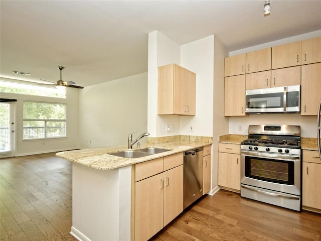 2209 Hancock Dr Unit 4, Austin, TX 78756 - kitchen featuring appliances with stainless steel finishes, a sink, light brown cabinets, and a peninsula