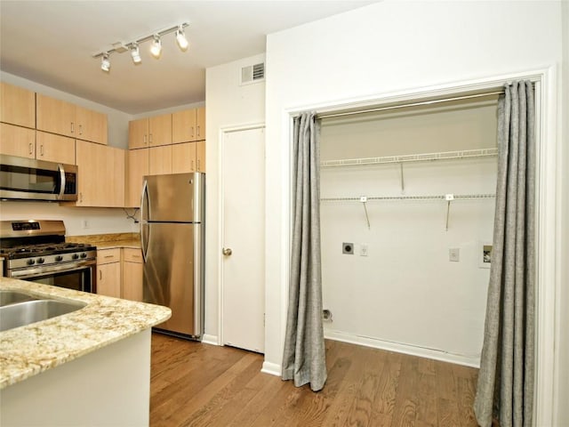 2209 Hancock Dr Unit 4, Austin, TX 78756 - kitchen featuring appliances with stainless steel finishes, light brown cabinetry, wood finished floors, and light stone countertops