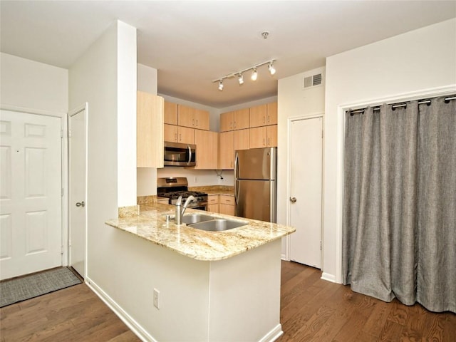 2209 Hancock Dr Unit 4, Austin, TX 78756 - kitchen featuring appliances with stainless steel finishes, light brown cabinets, a sink, dark wood-type flooring, and a peninsula
