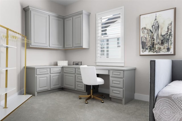 home office with built in study area, baseboards, and light carpet
