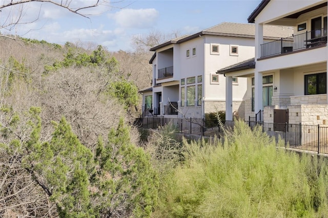 rear view of property featuring stucco siding and stone siding