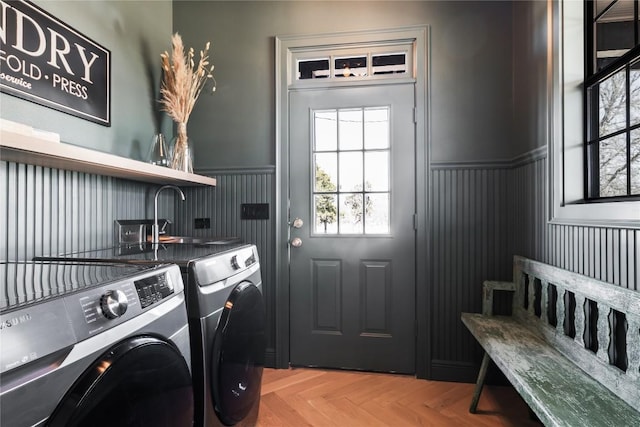 laundry room featuring a wainscoted wall, separate washer and dryer, and laundry area
