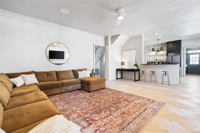 living area featuring recessed lighting, ornamental molding, and a ceiling fan