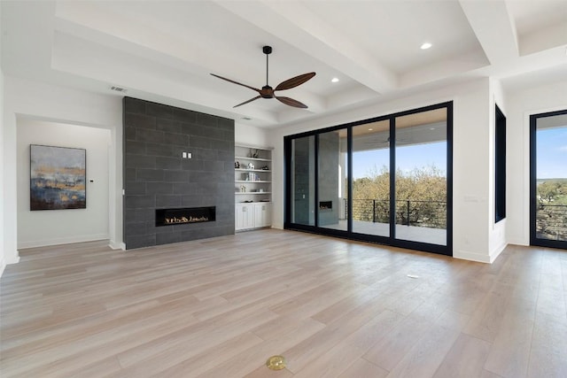 3113 Stableford Cv, Spicewood, TX 78669 - unfurnished living room with a ceiling fan, light wood-style floors, a fireplace, beamed ceiling, and recessed lighting