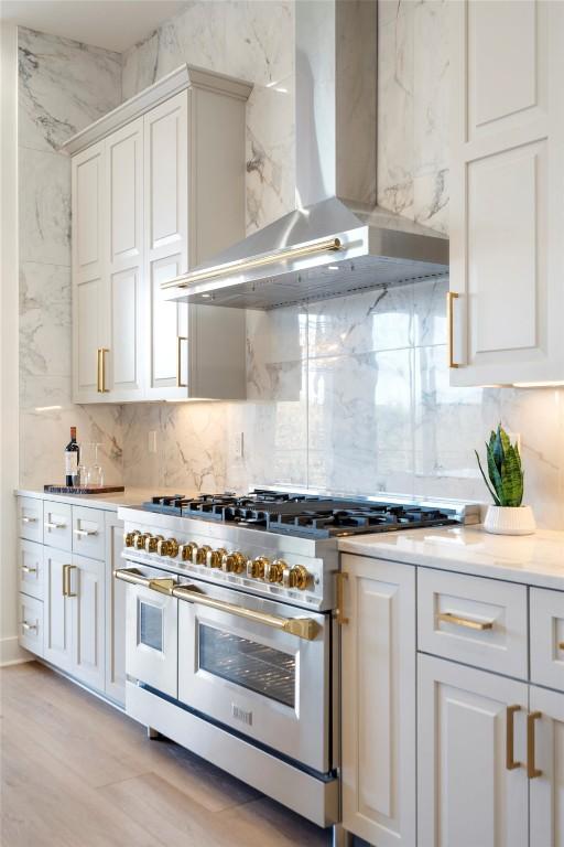 3113 Stableford Cv, Spicewood, TX 78669 - kitchen with wall chimney range hood, range with two ovens, tasteful backsplash, and white cabinets