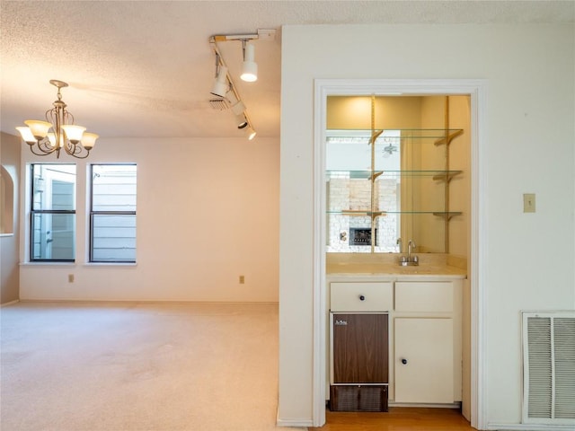 3379 S El Dorado, Lakeway, TX 78734 - indoor wet bar with a chandelier, decorative light fixtures, rail lighting, a textured ceiling, and light colored carpet