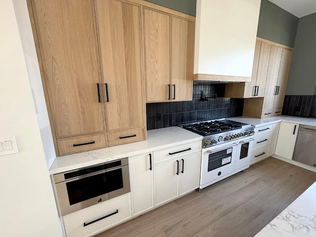 705 E 50th St, Austin, TX 78751 - kitchen featuring decorative backsplash, light stone countertops, appliances with stainless steel finishes, and custom range hood