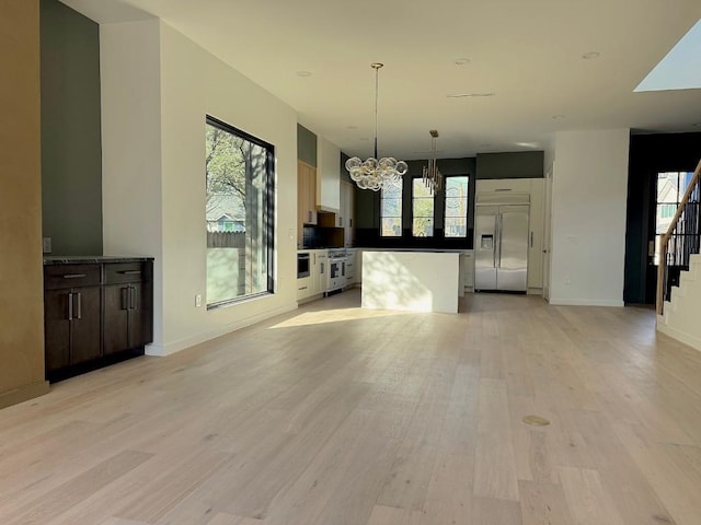 705 E 50th St, Austin, TX 78751 - unfurnished living room featuring light wood-type flooring, an inviting chandelier, a healthy amount of sunlight, and stairway