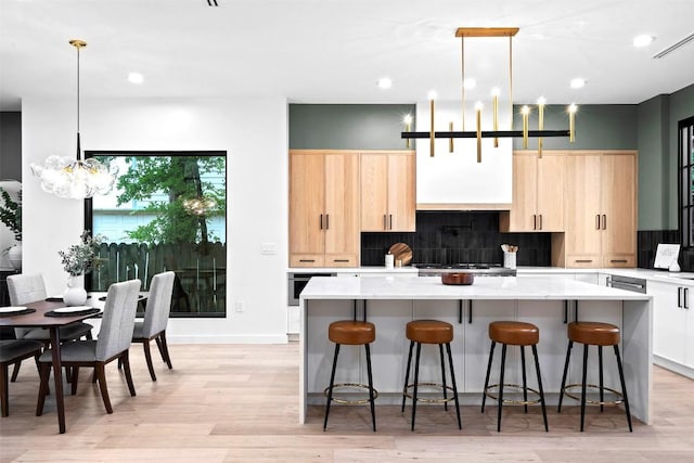 705 E 50th St, Austin, TX 78751 - kitchen featuring light brown cabinetry, a kitchen island, tasteful backsplash, a chandelier, and a kitchen bar