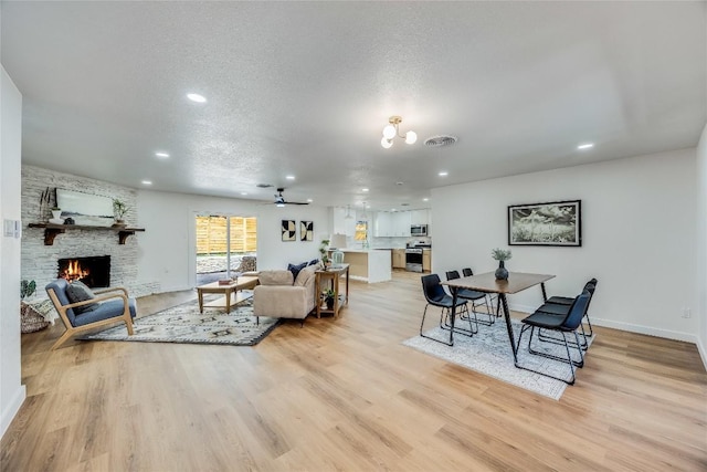 11704 Indianhead Dr, Austin, TX 78753 - living room with light wood-style flooring, recessed lighting, a stone fireplace, a textured ceiling, and ceiling fan