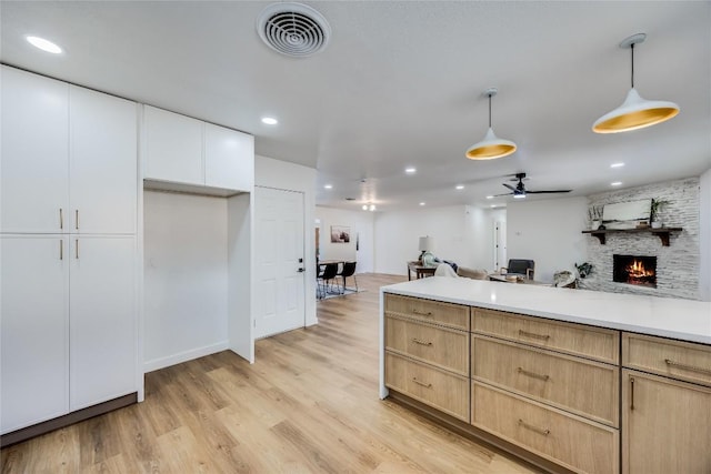 11704 Indianhead Dr, Austin, TX 78753 - kitchen featuring open floor plan, a fireplace, pendant lighting, light wood-style flooring, and white cabinets