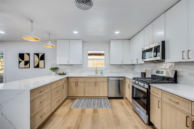 11704 Indianhead Dr, Austin, TX 78753 - kitchen featuring stainless steel appliances, light brown cabinets, light wood finished floors, a peninsula, and recessed lighting