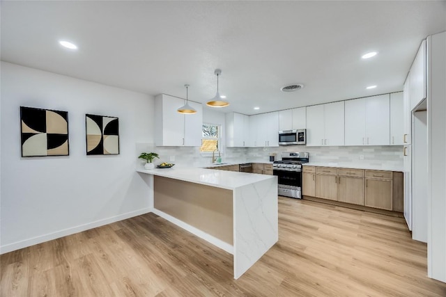 11704 Indianhead Dr, Austin, TX 78753 - kitchen featuring stainless steel appliances, a peninsula, light wood-style floors, tasteful backsplash, and recessed lighting