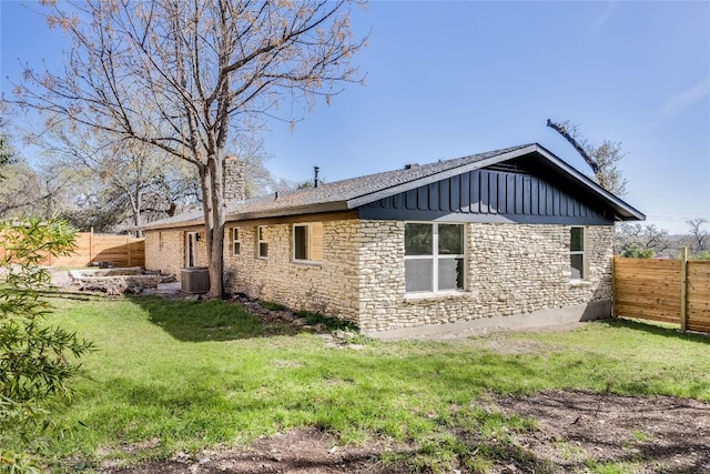 view of home's exterior featuring a lawn, central AC unit, fence, and stone siding