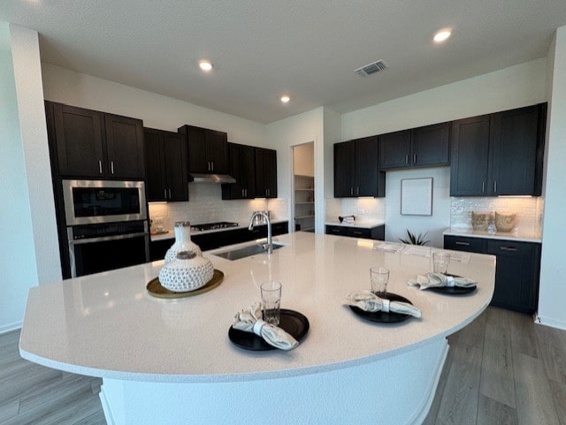 2705 Sage Ranch Dr Unit 26, Leander, TX 78641 - kitchen with light wood-style floors, tasteful backsplash, a spacious island, and recessed lighting