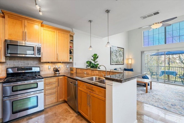 kitchen with a sink, backsplash, a peninsula, appliances with stainless steel finishes, and visible vents