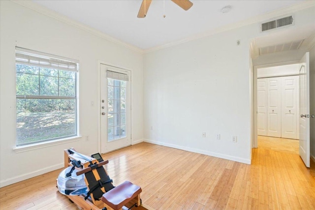 interior space with light wood-type flooring, a ceiling fan, visible vents, and ornamental molding