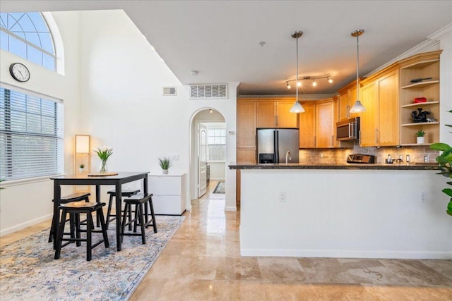 kitchen with open shelves, arched walkways, visible vents, and appliances with stainless steel finishes