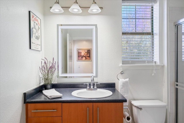 bathroom featuring a textured wall, a wealth of natural light, toilet, and vanity