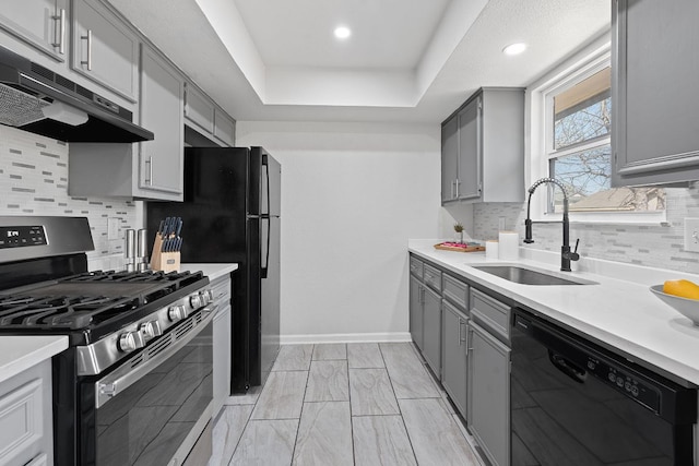 1002 Parkside Cir, Round Rock, TX 78664 - kitchen featuring gas range, black dishwasher, gray cabinetry, under cabinet range hood, and backsplash