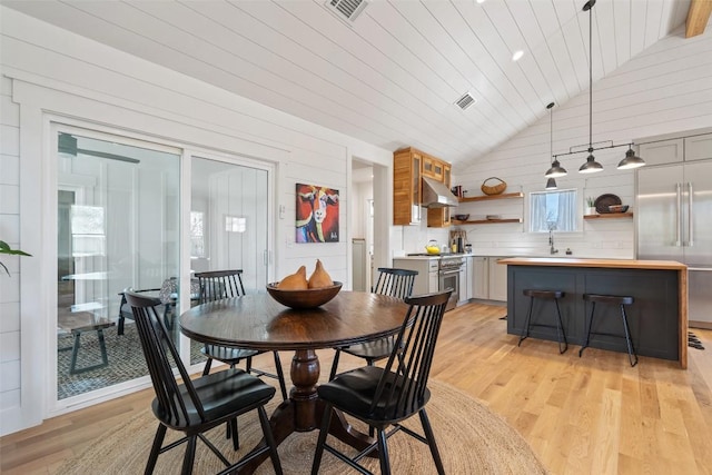 703 E 15th St, Georgetown, TX 78626 - dining room with lofted ceiling, light wood-type flooring, wooden walls, and wood ceiling