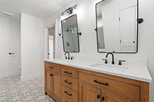 703 E 15th St, Georgetown, TX 78626 - bathroom featuring double vanity, baseboards, and toilet