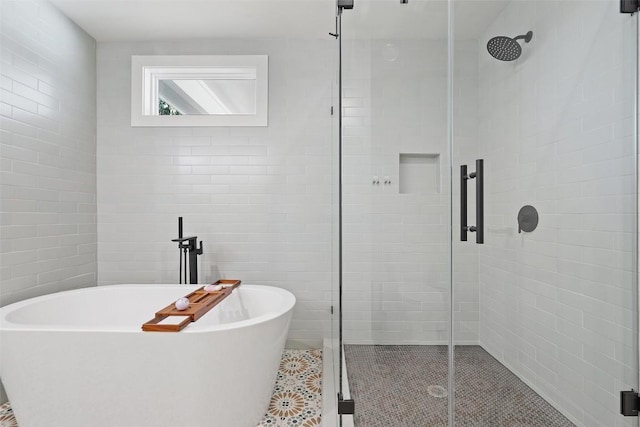 703 E 15th St, Georgetown, TX 78626 - bathroom featuring a shower stall, a soaking tub, tile patterned flooring, and tile walls