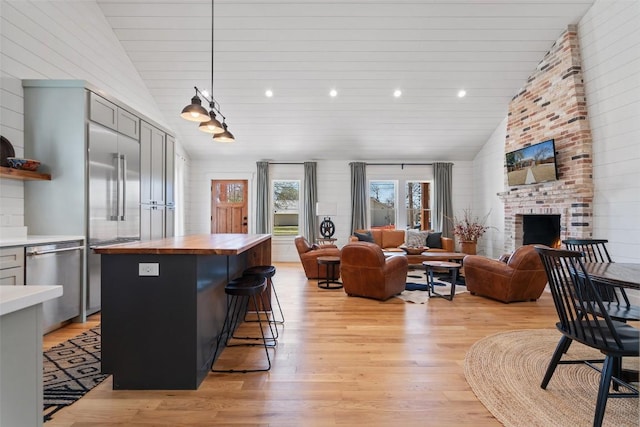 703 E 15th St, Georgetown, TX 78626 - kitchen with wooden counters, stainless steel dishwasher, vaulted ceiling, light wood-style flooring, and a center island