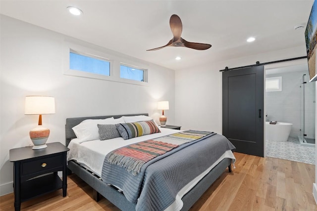 703 E 15th St, Georgetown, TX 78626 - bedroom featuring a barn door, multiple windows, light wood finished floors, ceiling fan, and recessed lighting