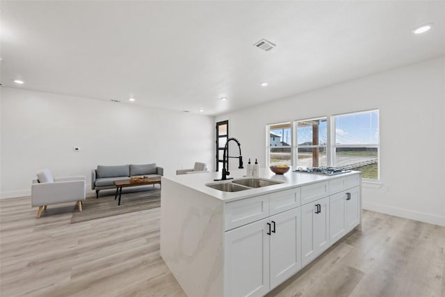 195 Bianca Cir, Del Valle, TX 78617 - kitchen featuring stainless steel gas cooktop, white cabinetry, recessed lighting, a kitchen island with sink, and light wood-style flooring