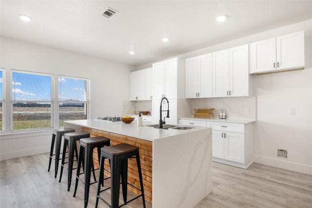 195 Bianca Cir, Del Valle, TX 78617 - kitchen featuring light wood-style floors, an island with sink, white cabinetry, a breakfast bar area, and recessed lighting
