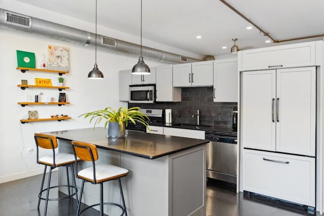 1601 E Cesar Chavez St Unit 202, Austin, TX 78702 - kitchen with stainless steel appliances, dark countertops, finished concrete flooring, a kitchen breakfast bar, and pendant lighting
