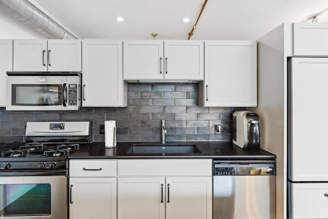 1601 E Cesar Chavez St Unit 202, Austin, TX 78702 - kitchen with appliances with stainless steel finishes, white cabinetry, dark countertops, tasteful backsplash, and recessed lighting