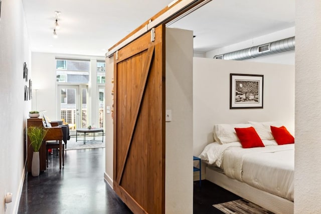1601 E Cesar Chavez St Unit 202, Austin, TX 78702 - bedroom featuring a barn door, rail lighting, and concrete flooring