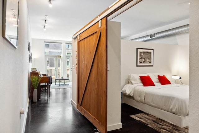 1601 E Cesar Chavez St Unit 202, Austin, TX 78702 - bedroom with a barn door, finished concrete floors, and rail lighting