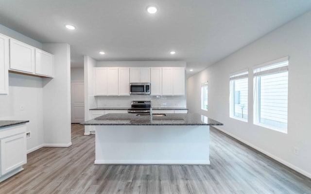 201 Lt Rusty Dr, Jarrell, TX 76537 - kitchen featuring stainless steel appliances, dark stone countertops, light wood finished floors, baseboards, and white cabinetry