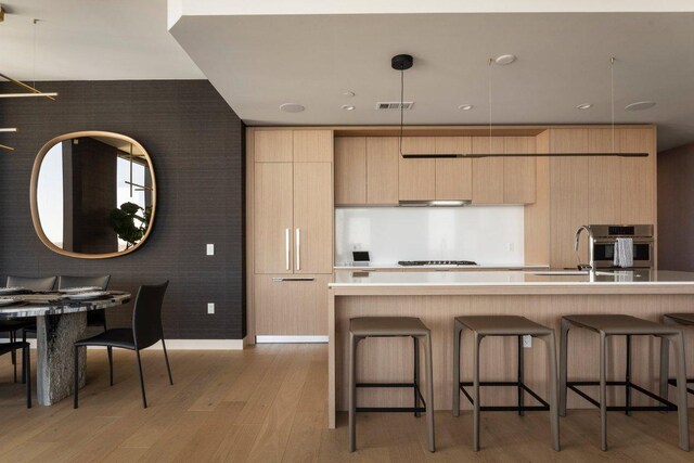 44 E Ave Unit 2601, Austin, TX 78701 - kitchen with modern cabinets, stainless steel oven, light brown cabinetry, and a kitchen breakfast bar