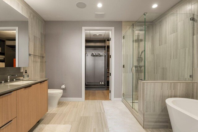 44 E Ave Unit 2601, Austin, TX 78701 - bathroom with a spacious closet, vanity, a stall shower, a soaking tub, and wood finished floors