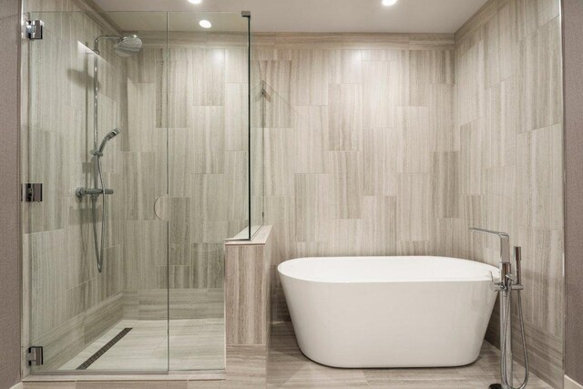 44 E Ave Unit 2601, Austin, TX 78701 - full bath with a freestanding tub, a shower stall, tile walls, and recessed lighting