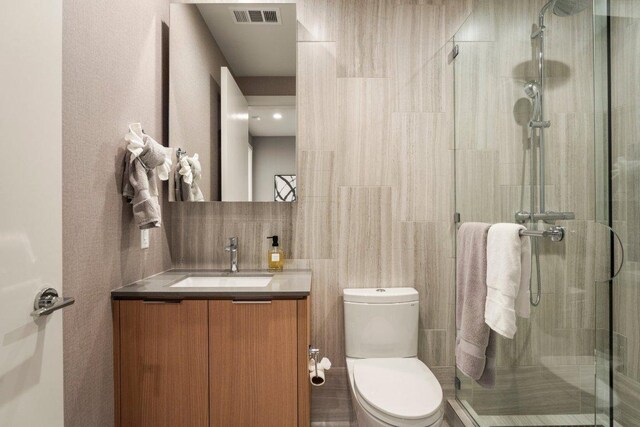 44 E Ave Unit 2601, Austin, TX 78701 - bathroom featuring vanity, toilet, a stall shower, and tile walls