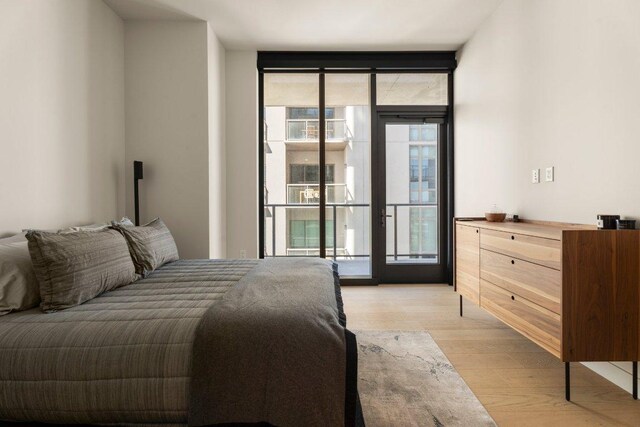 44 E Ave Unit 2601, Austin, TX 78701 - bedroom featuring floor to ceiling windows, access to exterior, light wood finished floors, and multiple windows