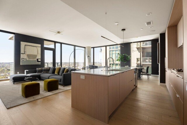 44 E Ave Unit 2601, Austin, TX 78701 - kitchen with a sink, modern cabinets, light wood-style floors, a large island, and expansive windows
