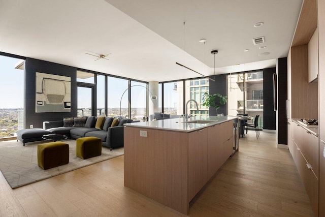 44 E Ave Unit 2601, Austin, TX 78701 - kitchen with a sink, modern cabinets, light wood-style flooring, a large island, and floor to ceiling windows